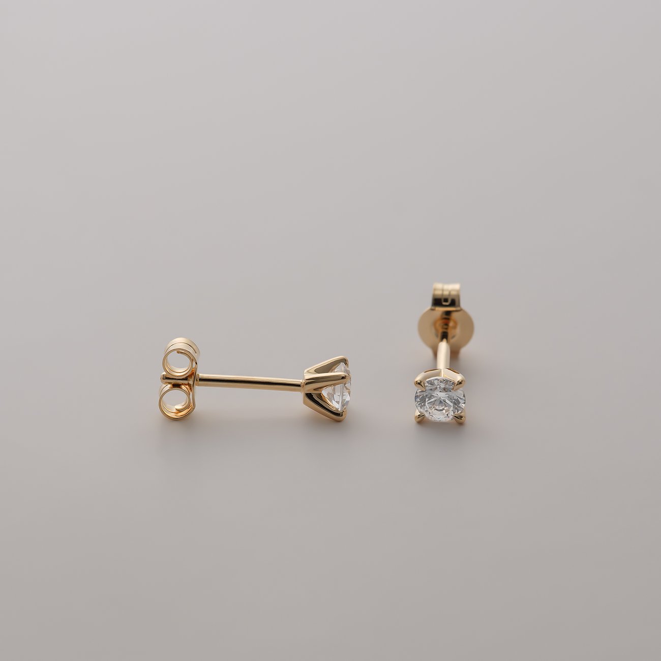 CHRIST Ohrstecker aus 585er Gelbgold mit funkelnden eingefassten Diamanten liegen auf einem hellen Untergrund.