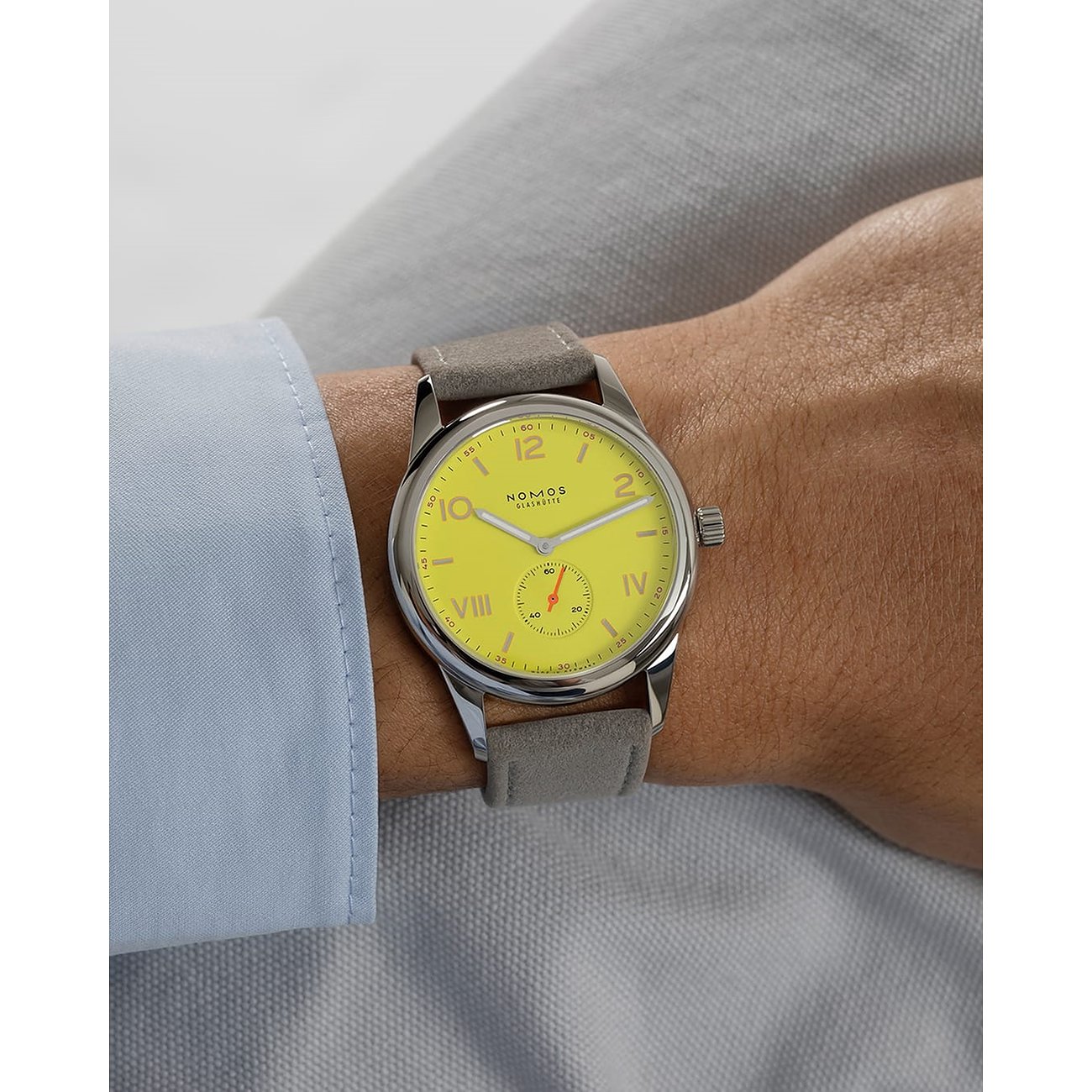 Nomos Glashütte Herrenuhr mit Edelstahlgehäuse, gelbes Zifferblatt und grauem Armband.