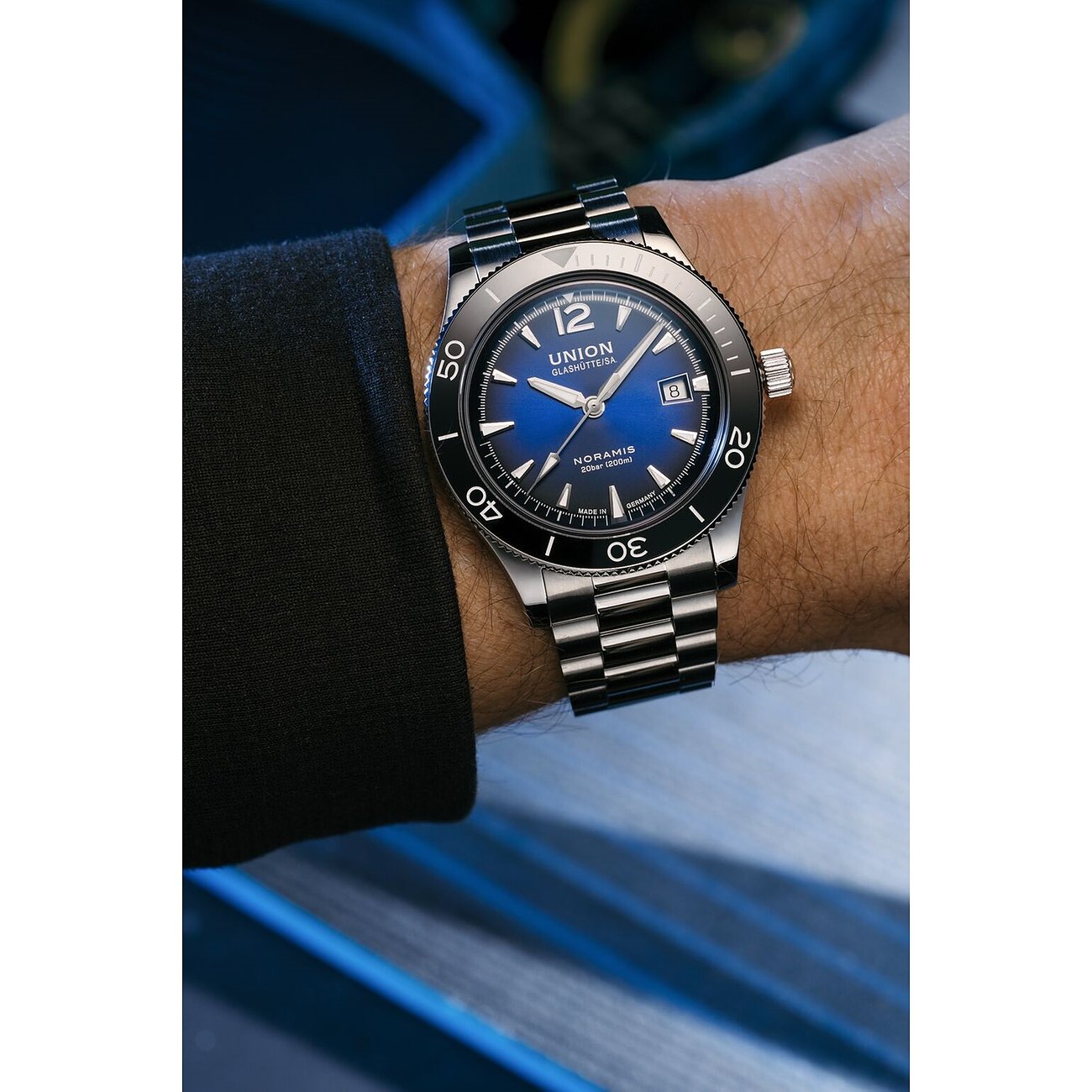 Union Glashütte Herrenuhr mit Edelstahlgehäuse, schwarzer Lünette und blauem Zifferblatt.