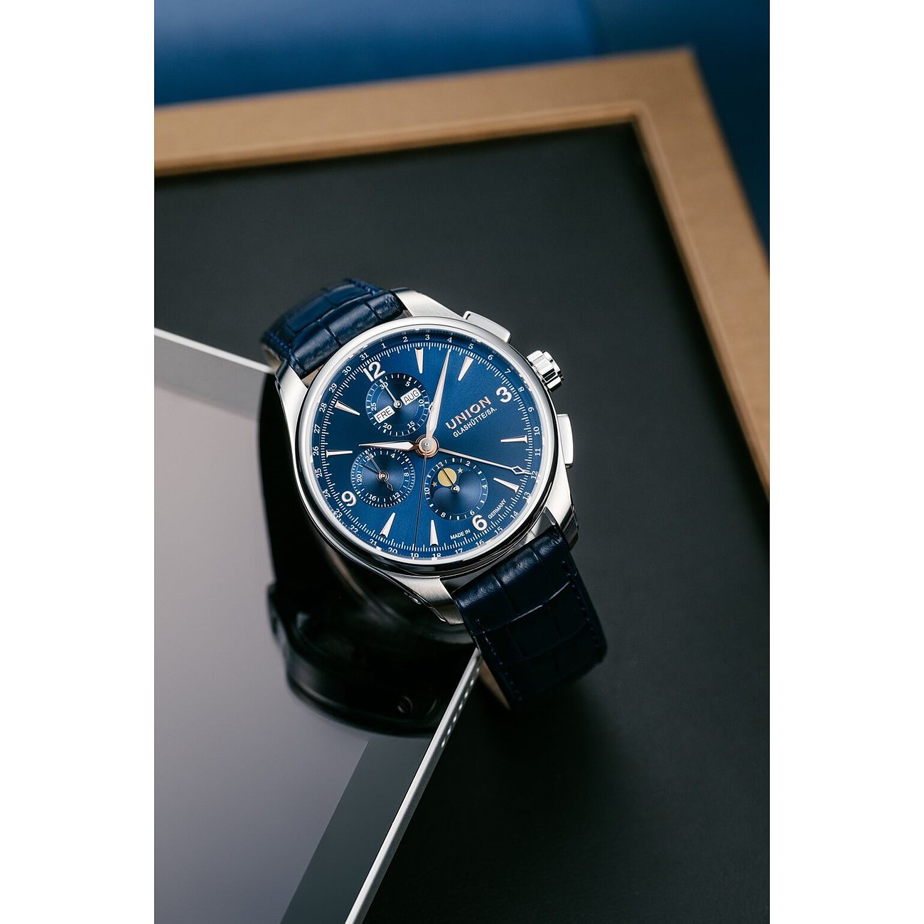 Union Glashütte Herrenuhr aus Edelstahl mit blauem Zifferblatt und Lederarmband, schräg auf einem Tablet platziert.