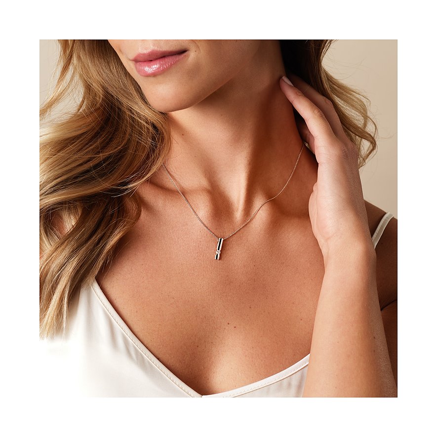 Gros plan d'une femme portant un collier CHRIST en or blanc 585, serti d'un diamant.