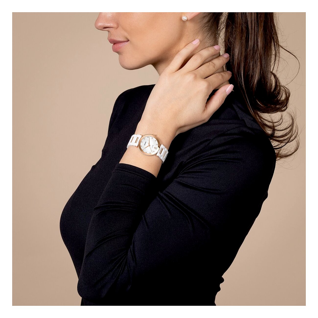 Seitenansicht einer Frau mit einer Rado Damenuhr aus weißer Keramik und diamantbesetztem Zifferblatt am Handgelenk.