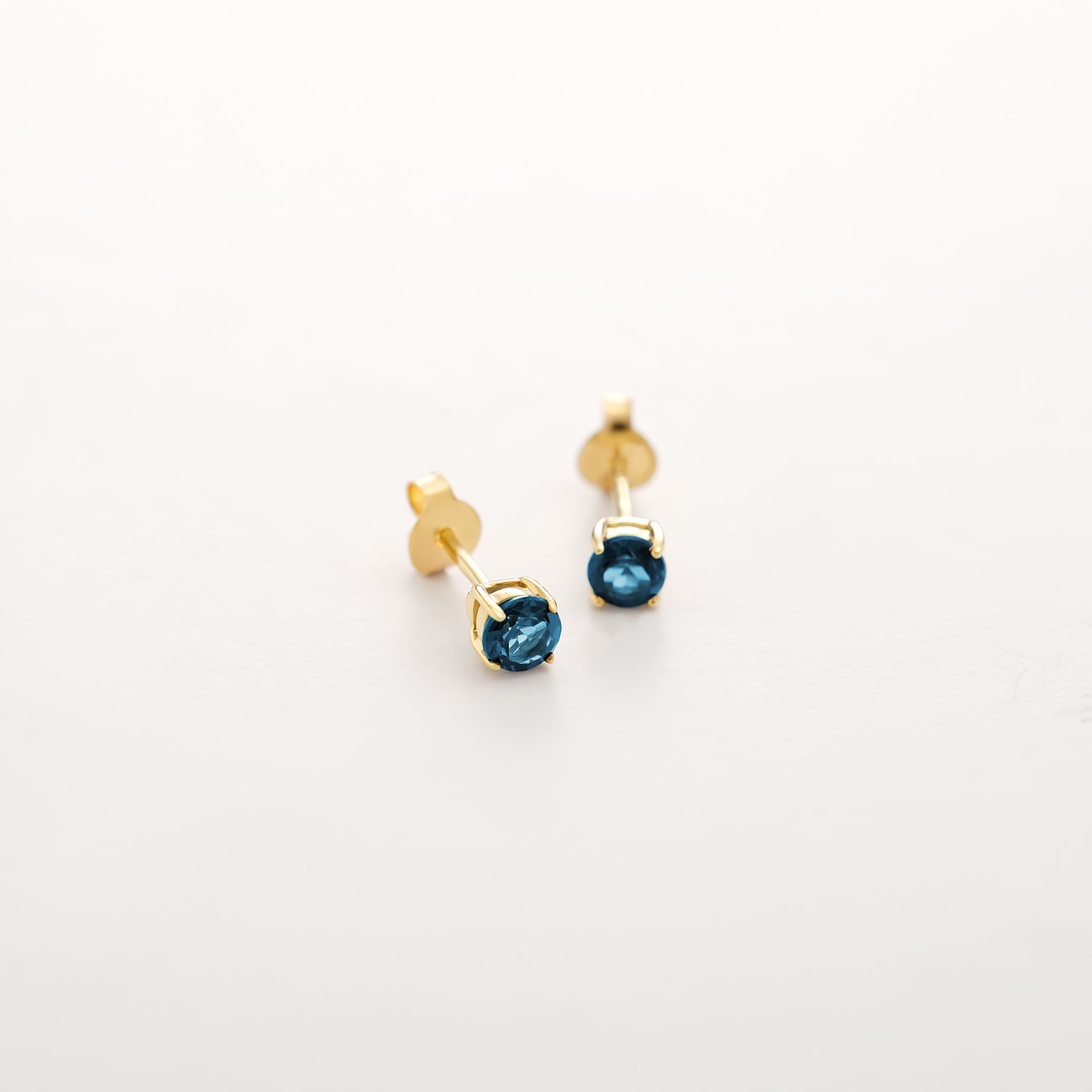 CHRIST Ohrstecker aus 375er Gelbgold mit facettierten blauen Topas-Farbsteinen auf weißem Hintergrund.