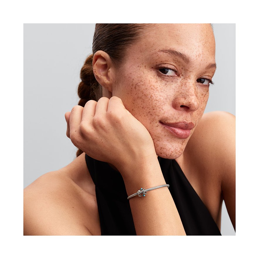 Nahaufnahme einer Frau mit Sommersprossen, ihr Arm ruht auf dem Kinn, ein silbernes Pandora Armband ziert ihr Handgelenk