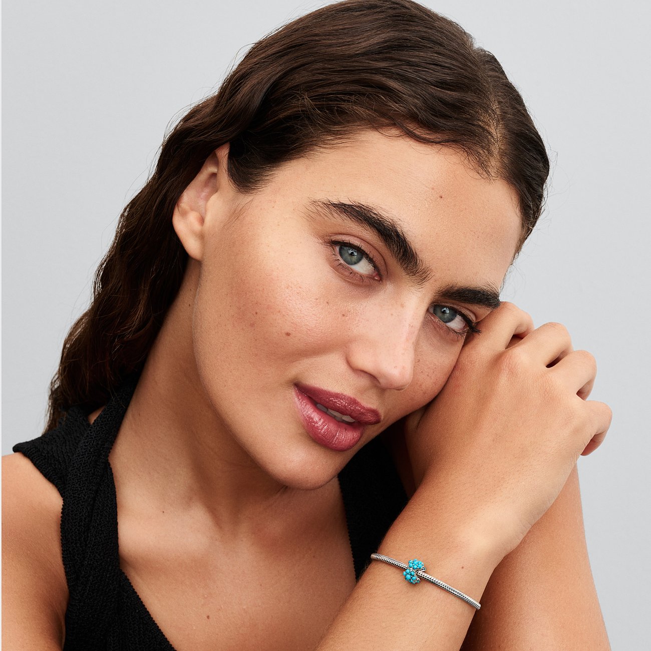 Nahaufnahme einer Frau mit einem Pandora Silber-Armband, das einen blauen Zirkonia-Farbstein-Anhänger hat.