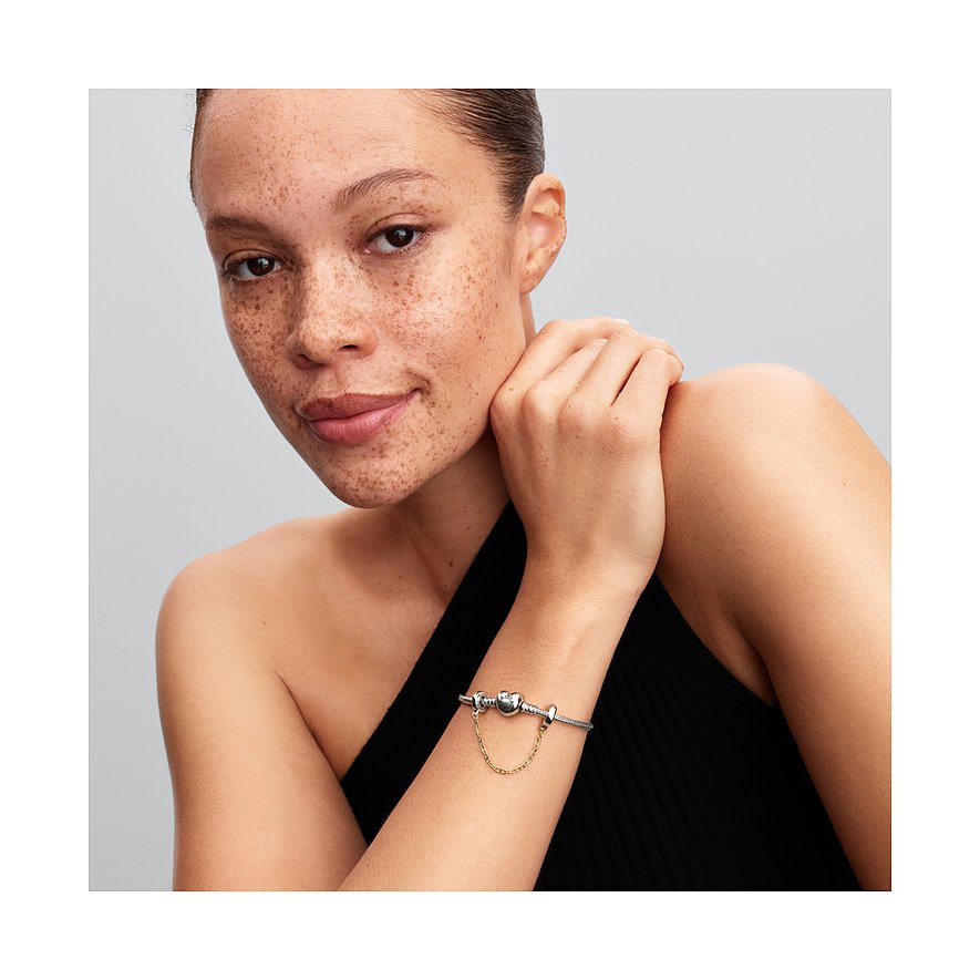 Eine Frau trägt ein Pandora Armband aus 925er Silber und Metall mit einem Herz-Anhänger und einer Kette.