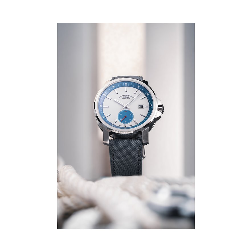 Mühle-Glashütte Herrenuhr mit Edelstahlgehäuse, weißem Zifferblatt und blauem Ring.