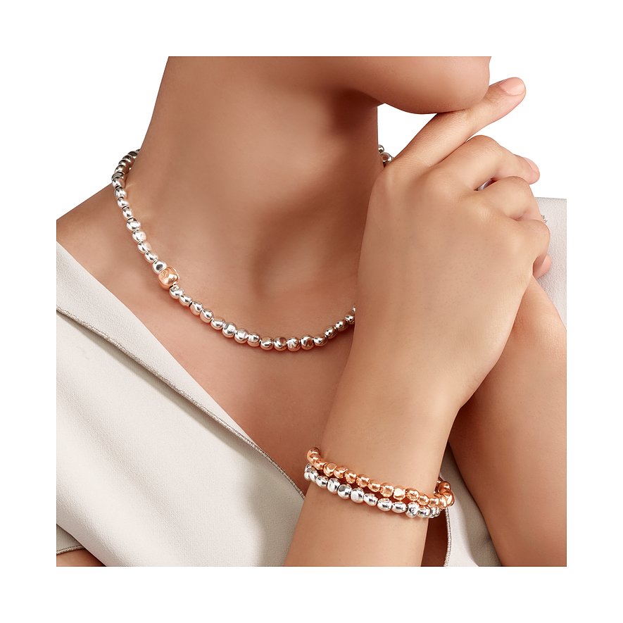 Am Hals einer Frau und am Handgelenk die DoDo Halskette und das Armband aus Silber und Roségold mit Kugelperlen.