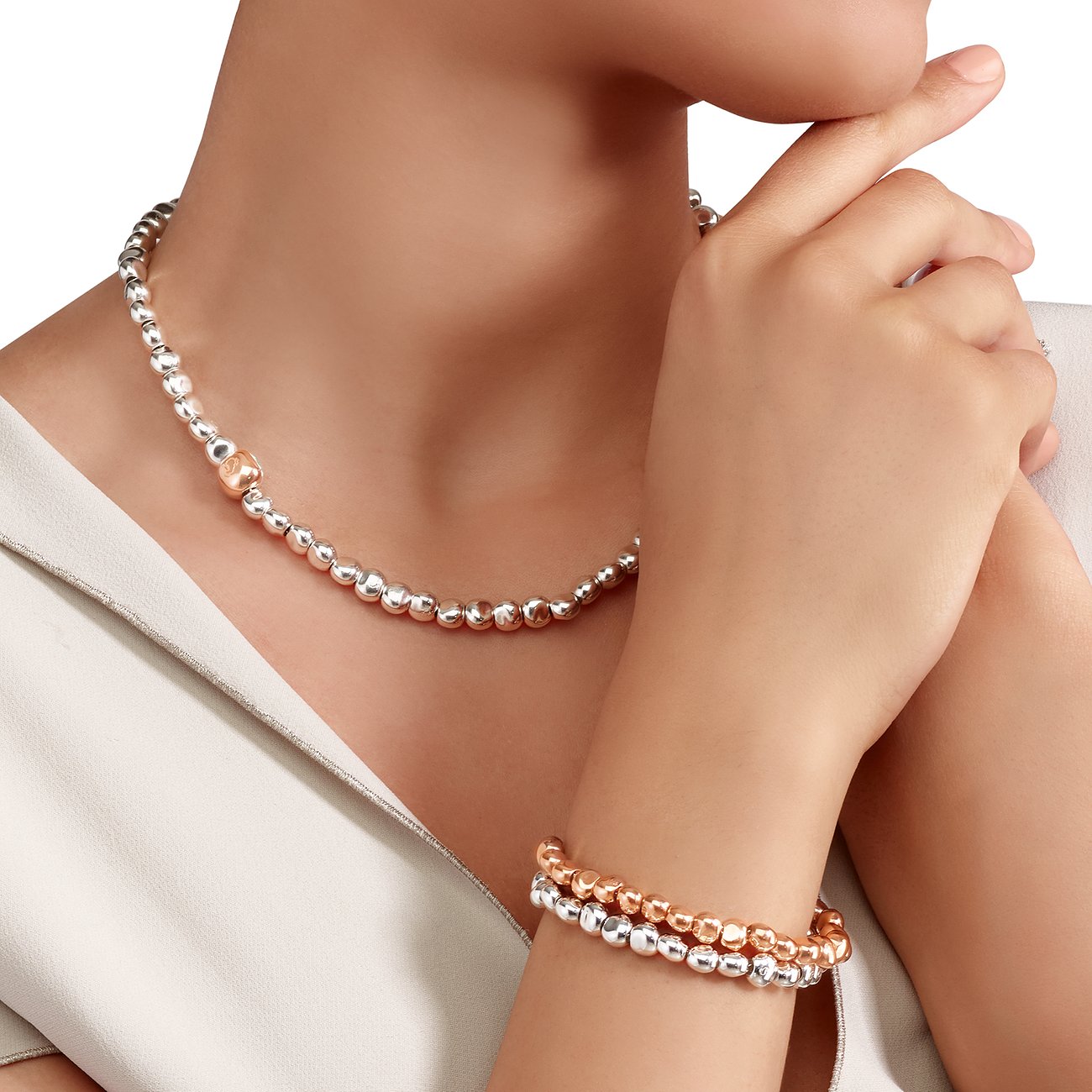 Am Hals einer Frau und am Handgelenk die DoDo Halskette und das Armband aus Silber und Roségold mit Kugelperlen.