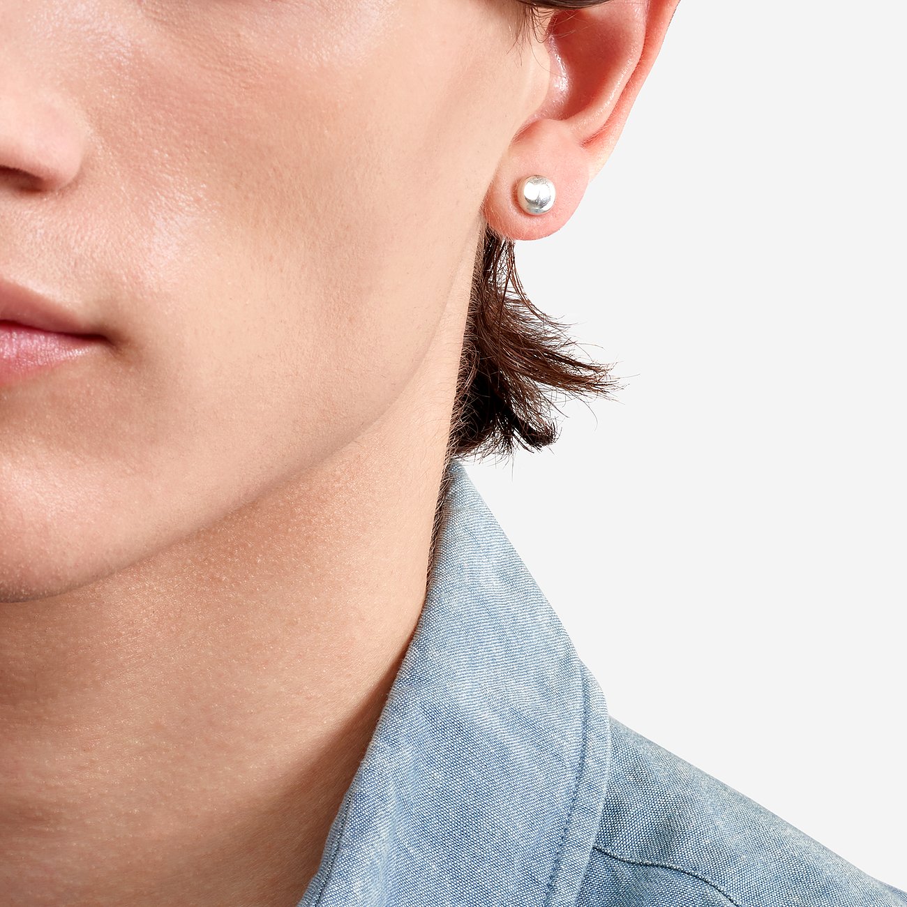 Close-up van een oor met een ronde, effen en glanzende DoDo oorknop van 925 zilver.