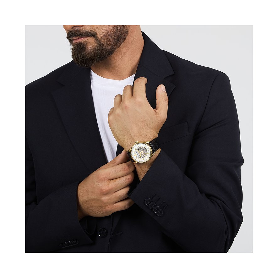 Mann mit Bart trägt goldene Lucien Rochat Herrenuhr mit schwarzem Lederarmband und sichtbarem Uhrwerk.