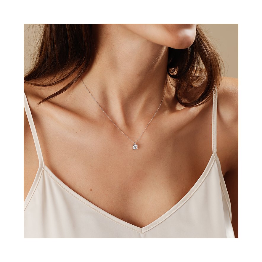 Ein CHRIST Halsschmuck aus 585er Weißgold mit einem glitzernden Diamantanhänger hängt am Hals einer Frau.