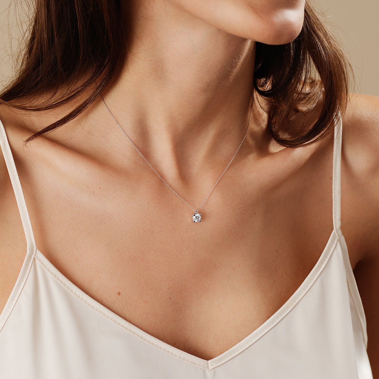 Ein CHRIST Halsschmuck aus 585er Weißgold mit einem glitzernden Diamantanhänger hängt am Hals einer Frau.