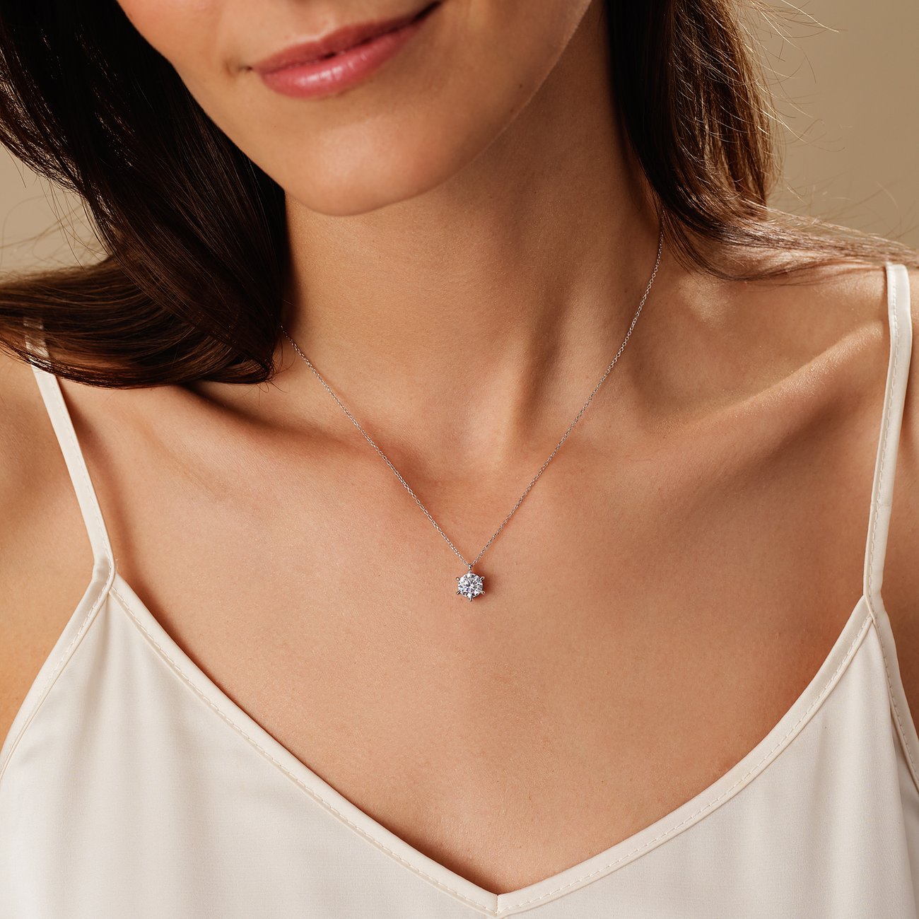 Nahaufnahme einer Frau, die eine CHRIST Halskette aus 585 Weißgold trägt, mit einem funkelnden Diamanten als Anhänger.