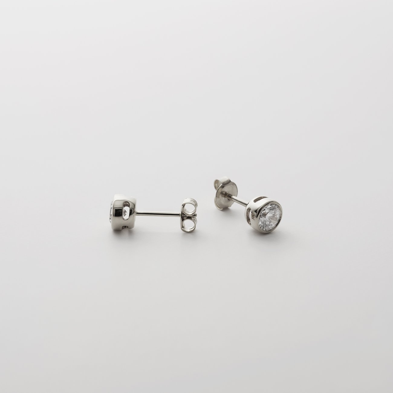 CHRIST Ohrschmuck aus 585 Weißgold mit eingefasstem Diamant-Ohrstecker und einem weiteren dahinter.