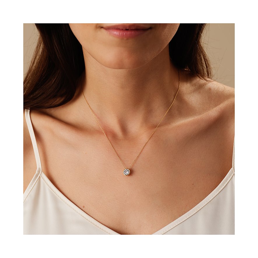 Nahaufnahme einer Frau, die eine CHRIST Halskette aus 585 Gelbgold mit einem runden Diamanten als Anhänger trägt.