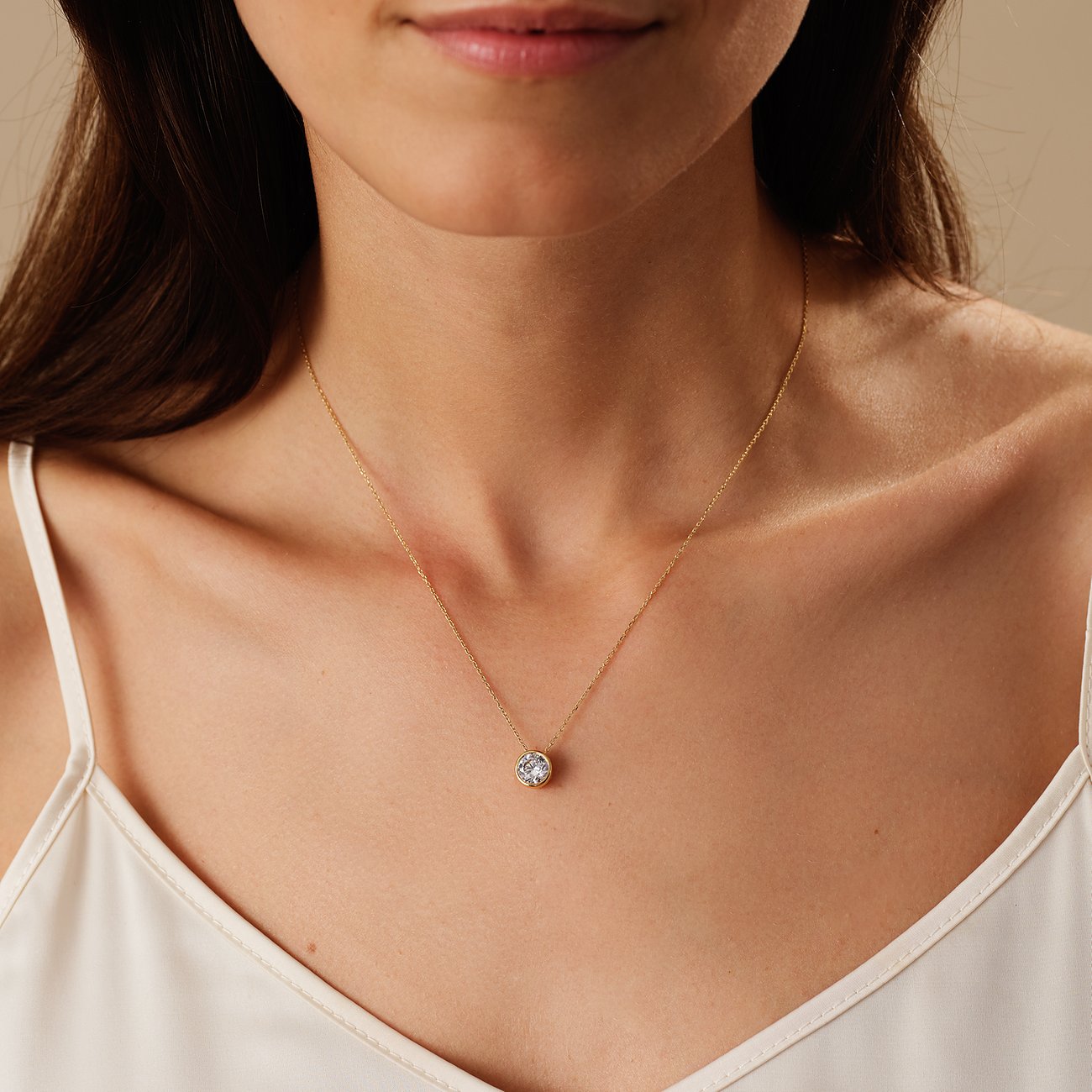 Nahaufnahme einer Frau, die eine CHRIST Halskette aus 585 Gelbgold mit einem runden Diamanten als Anhänger trägt.