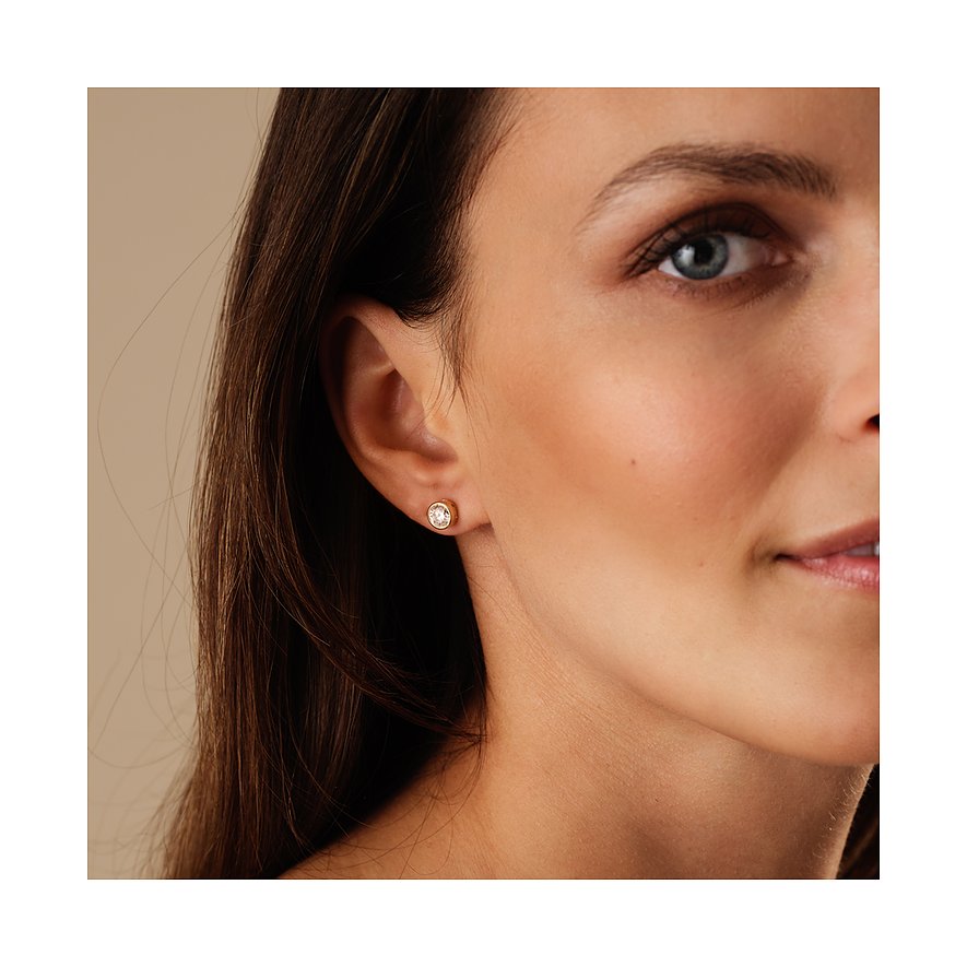 Nahaufnahme eines Ohres und Gesichts, die einen einzelnen CHRIST Ohrstecker aus Gelbgold mit einem Diamanten zeigt.