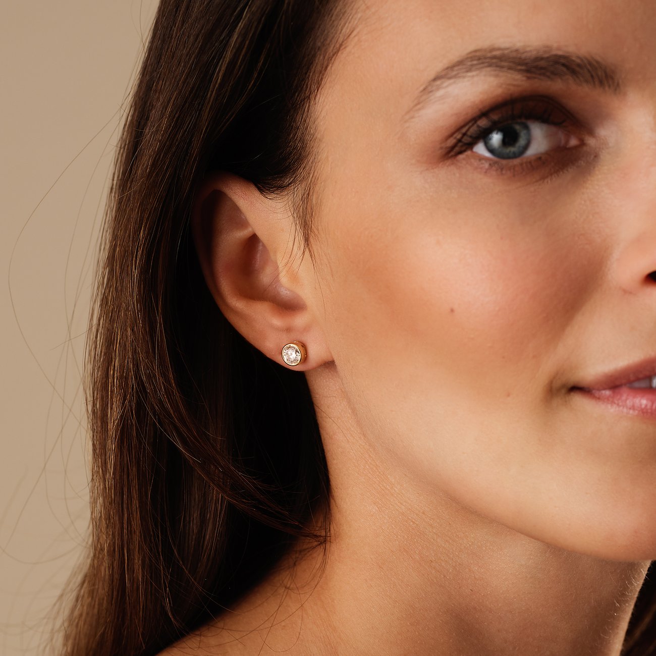 Nahaufnahme eines Ohres und Gesichts, die einen einzelnen CHRIST Ohrstecker aus Gelbgold mit einem Diamanten zeigt.