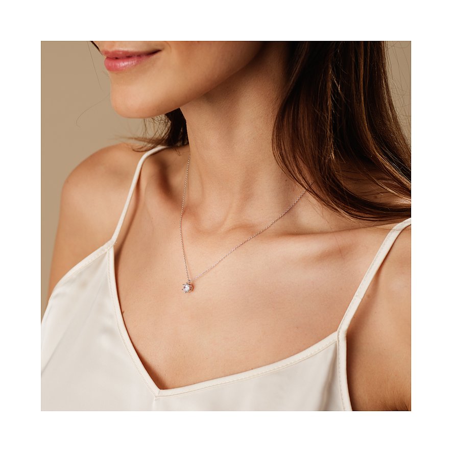 Nahaufnahme einer Frau, die eine CHRIST Weißgoldkette mit Diamanten und einem einzelnen runden Anhänger trägt.