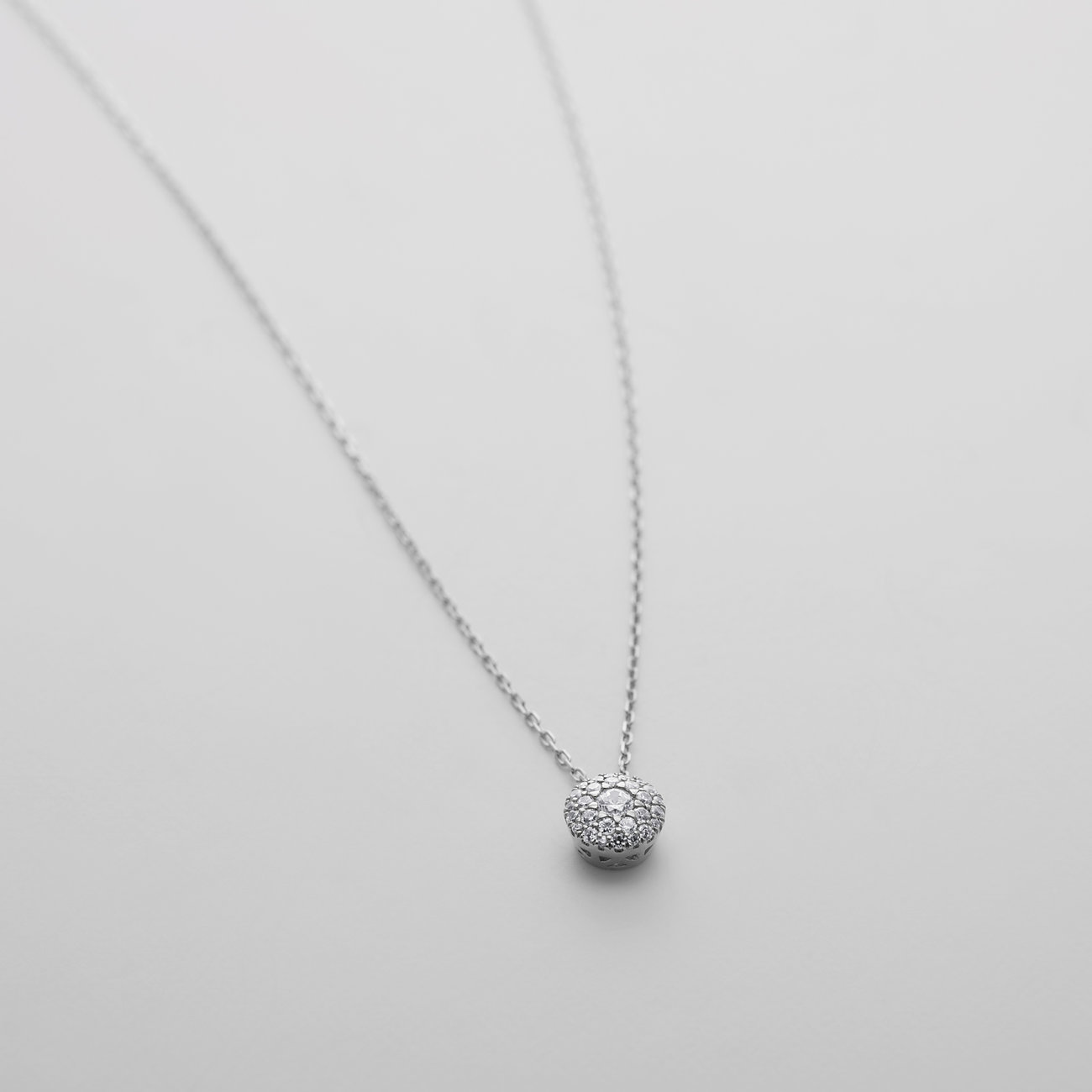 CHRIST Halskette aus 585er Weißgold mit funkelndem Diamant-Anhänger, kugelförmig und nah aufgenommen.