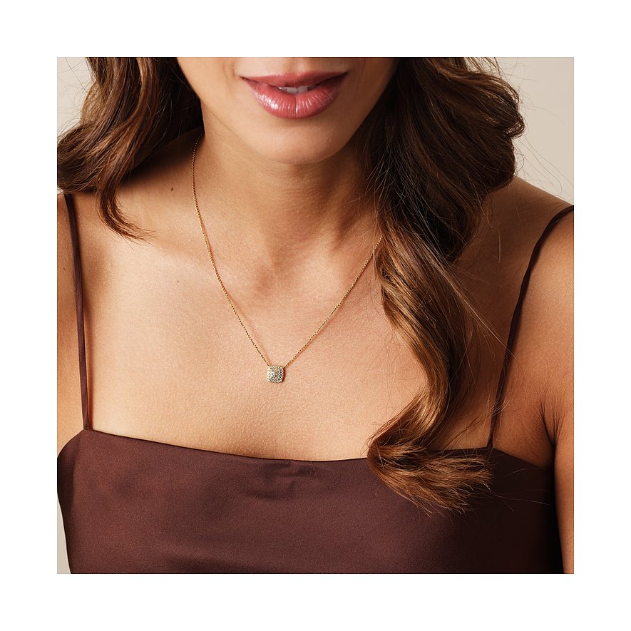 Eine Frau trägt eine CHRIST Halskette aus Gelbgold mit einem quadratischen Diamant-Anhänger, der auf ihrer Brust liegt.