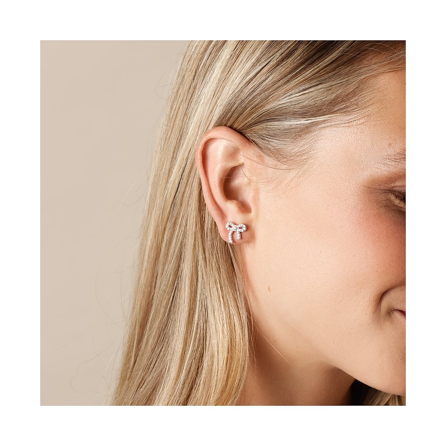 Ein CHRIST Schleifchen-Ohrstecker aus recyceltem Silber mit Zirkonia-Verzierung, getragen an einem Ohr.