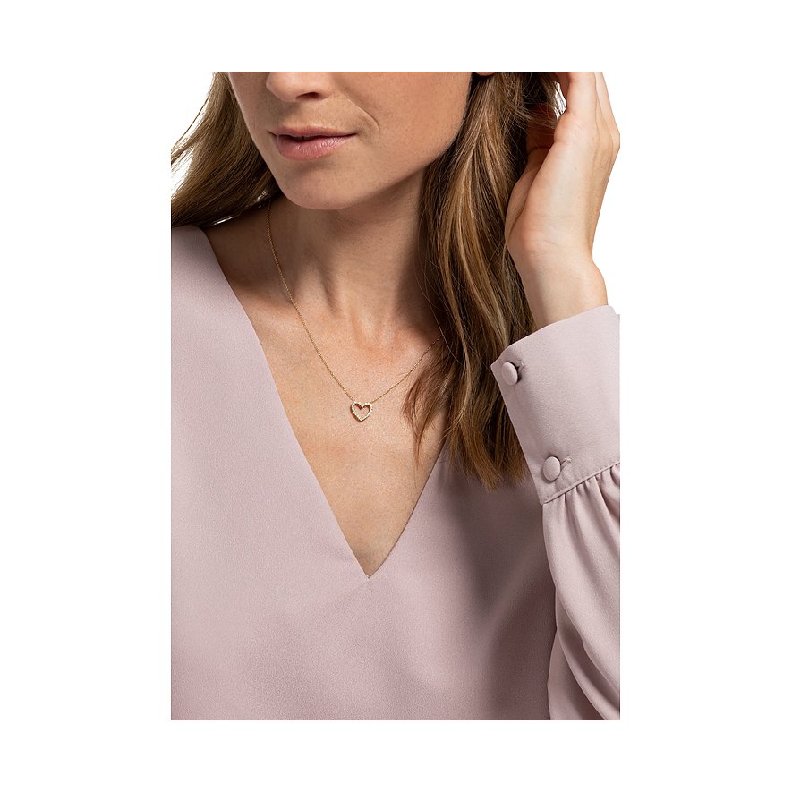 Ein CHRIST Halsschmuck aus Gelbgold mit funkelnden Diamanten in Herzform, getragen von einem Model.