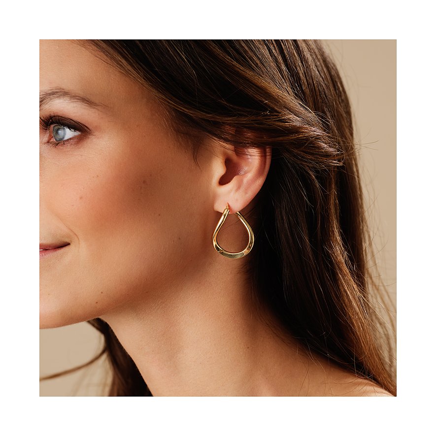 Nahaufnahme einer Frau, die am Ohr einen CHRIST Ohrring aus Gelbgold 585 trägt. Der Ohrring ist Tropfen-förmig.