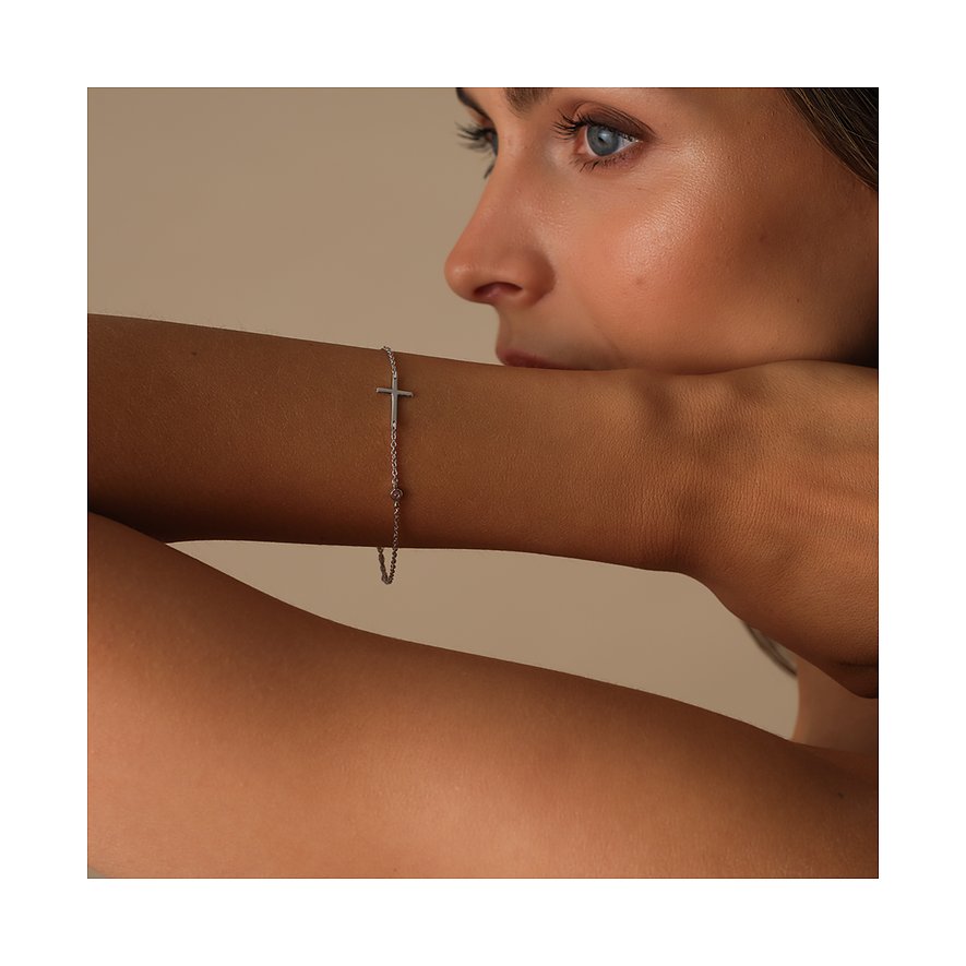 Ein zartes silbernes CHRIST Armband aus recyceltem Silber mit Kreuzanhänger und Zirkonia am Handgelenk eines Models.