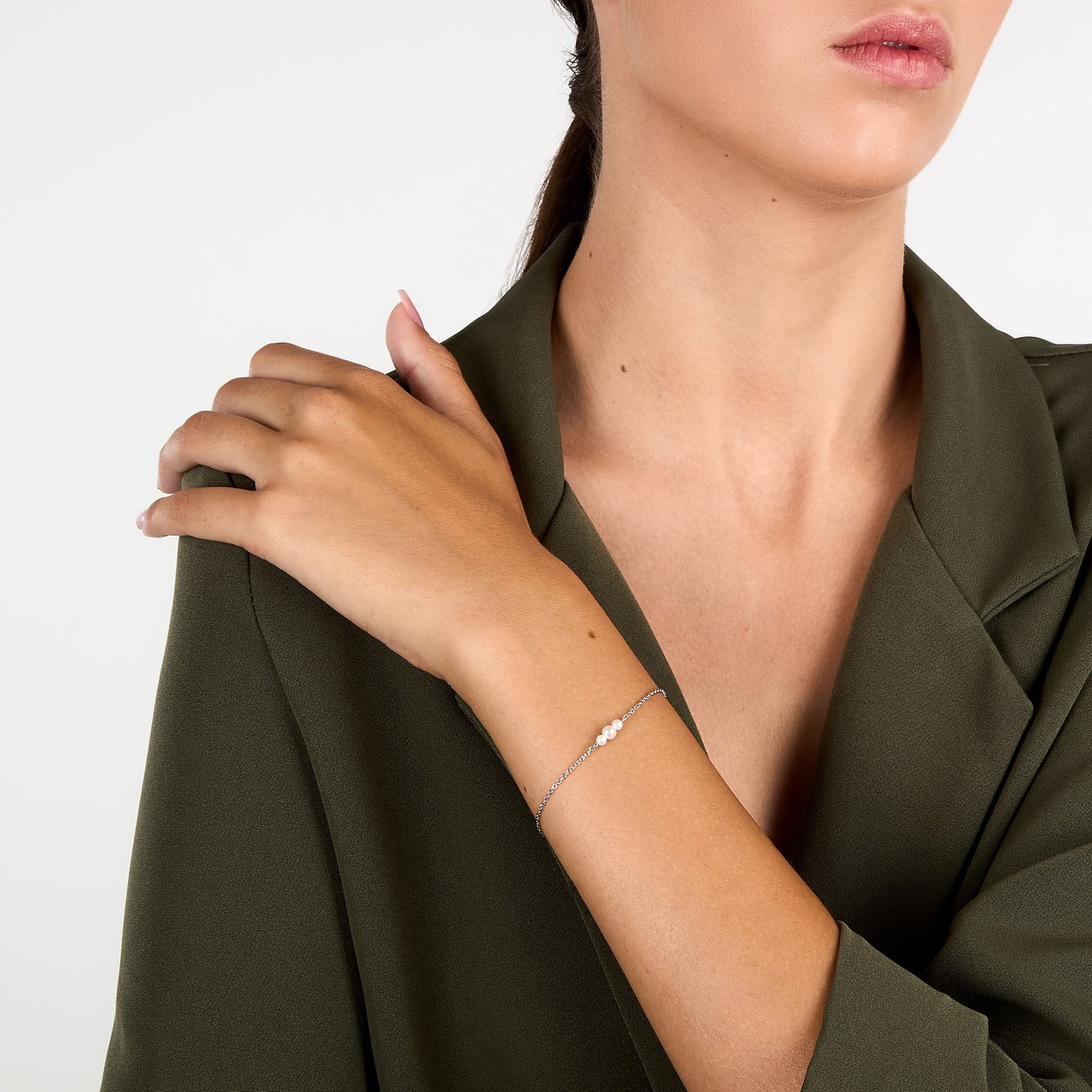 Am Handgelenk einer Frau getragenes La Petite Story Armband aus rhodiniertem Silber mit drei weißen Perlen.