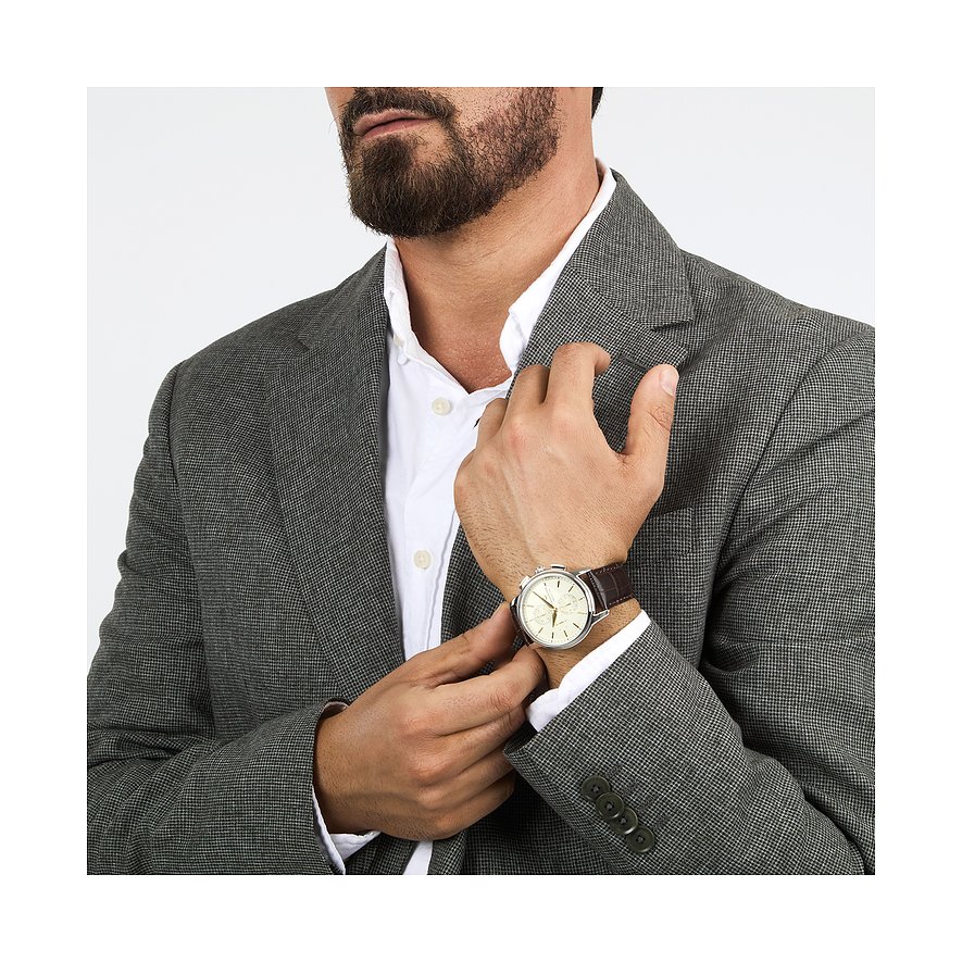 Nahaufnahme eines Mannes, der eine Lucien Rochat Herrenuhr aus Edelstahl mit braunem Armband am Handgelenk trägt.