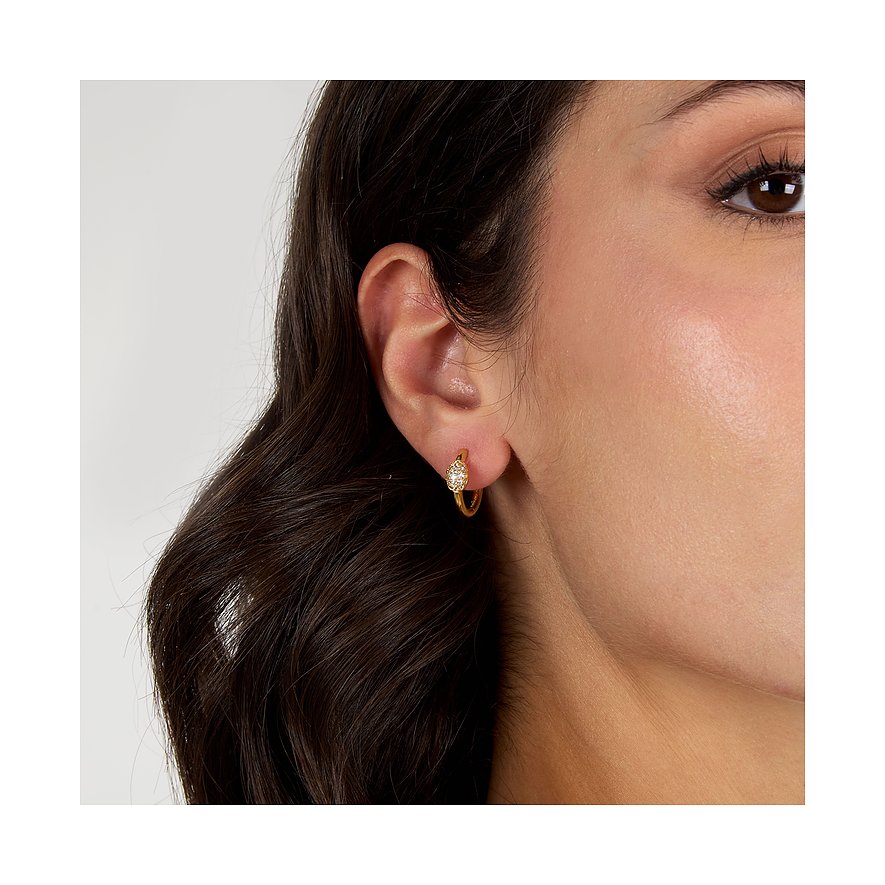 En kvinna bär ett litet, gyllene Morellato creolörhänge av återvunnet silver med gnistrande zirkonstenar.