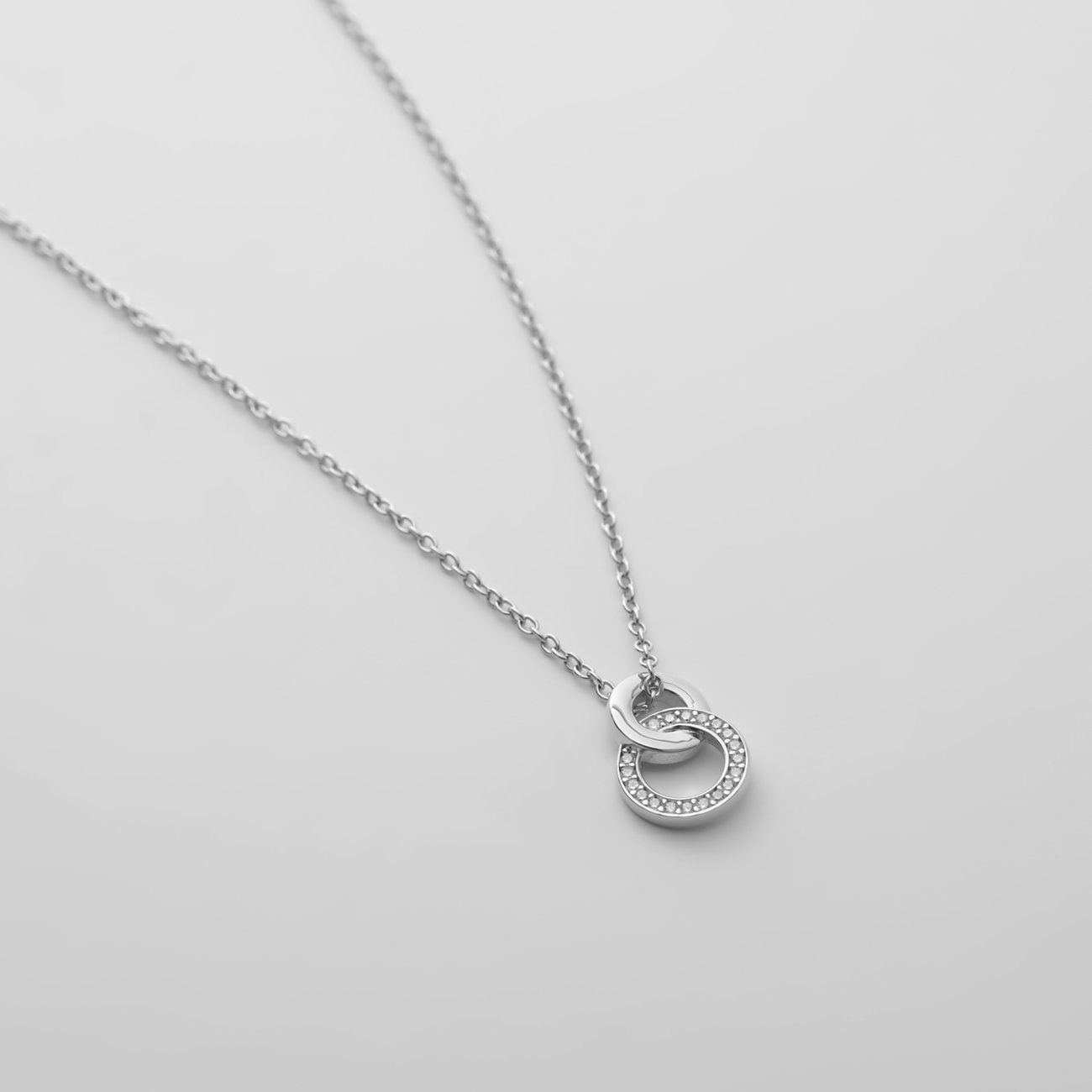 Collana JETTE in argento 925 riciclato con due anelli intrecciati, uno con pavé di zirconi.