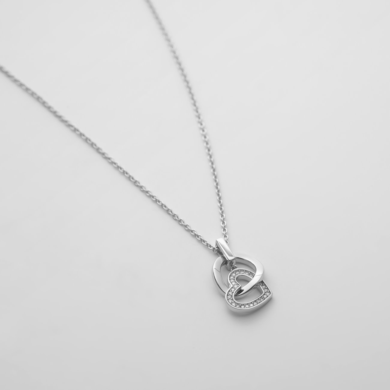 JETTE Halsschmuck aus recyceltem Silber: filigrane Halskette mit zwei ineinander verschlungenen Herzen, eines mit Zirkonia.
