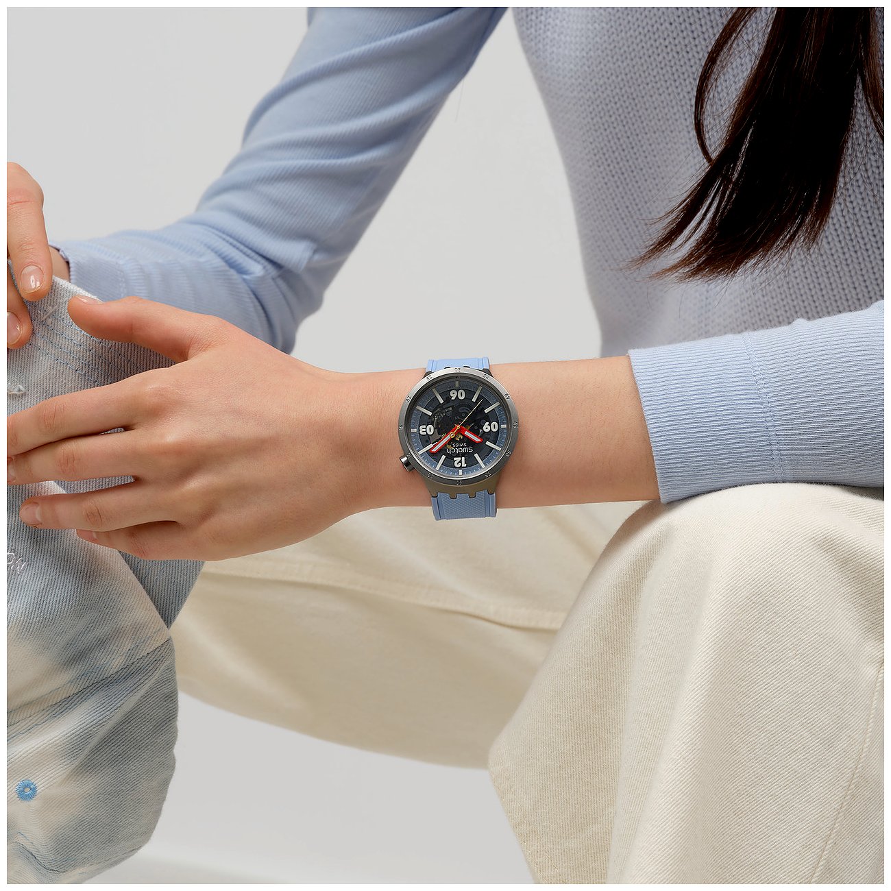 Swatch-klocka med boett i rostfritt stål, analog urtavla och blått armband.