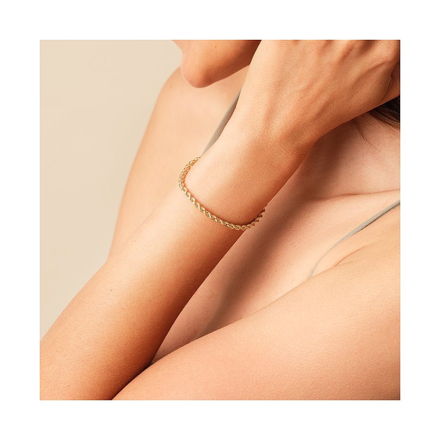 Am Arm einer Person getragenes CHRIST Armband aus gedrehtem Gelbgold, das elegant die Haut umschmeichelt.