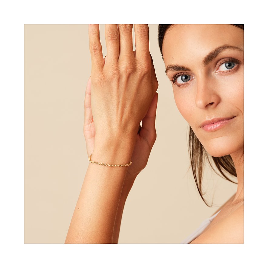 Nahaufnahme einer Frau, die am rechten Handgelenk ein gedrehtes Kordelarmband aus 585 Gelbgold von CHRIST trägt.