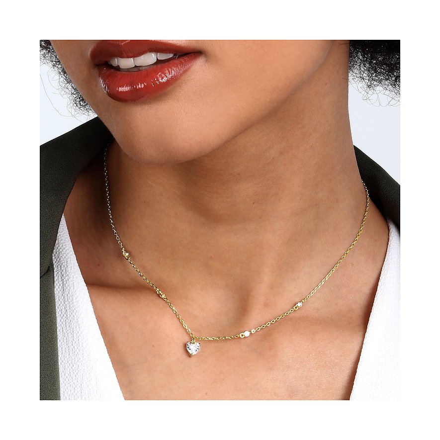 Model trägt eine goldene CHRIST Halsschmuck Kette aus recyceltem Silber mit Zirkonia-Herzanhänger.