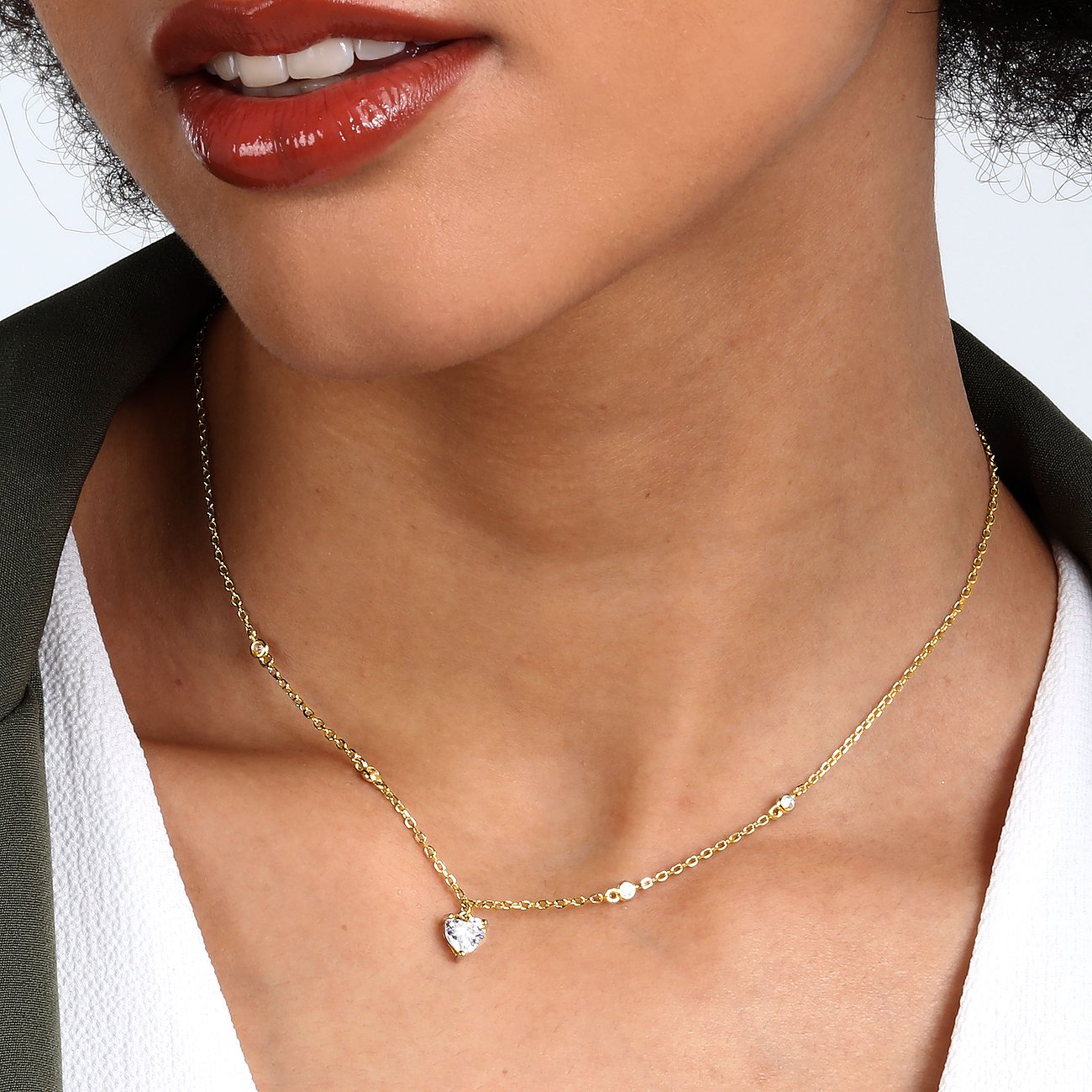 Model trägt eine goldene CHRIST Halsschmuck Kette aus recyceltem Silber mit Zirkonia-Herzanhänger.
