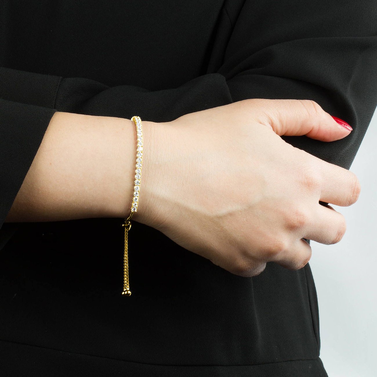 Frauenarm, mit einem CHRIST Armband aus vergoldetem recyceltem Silber, verziert mit Zirkonia-Farbsteinen.