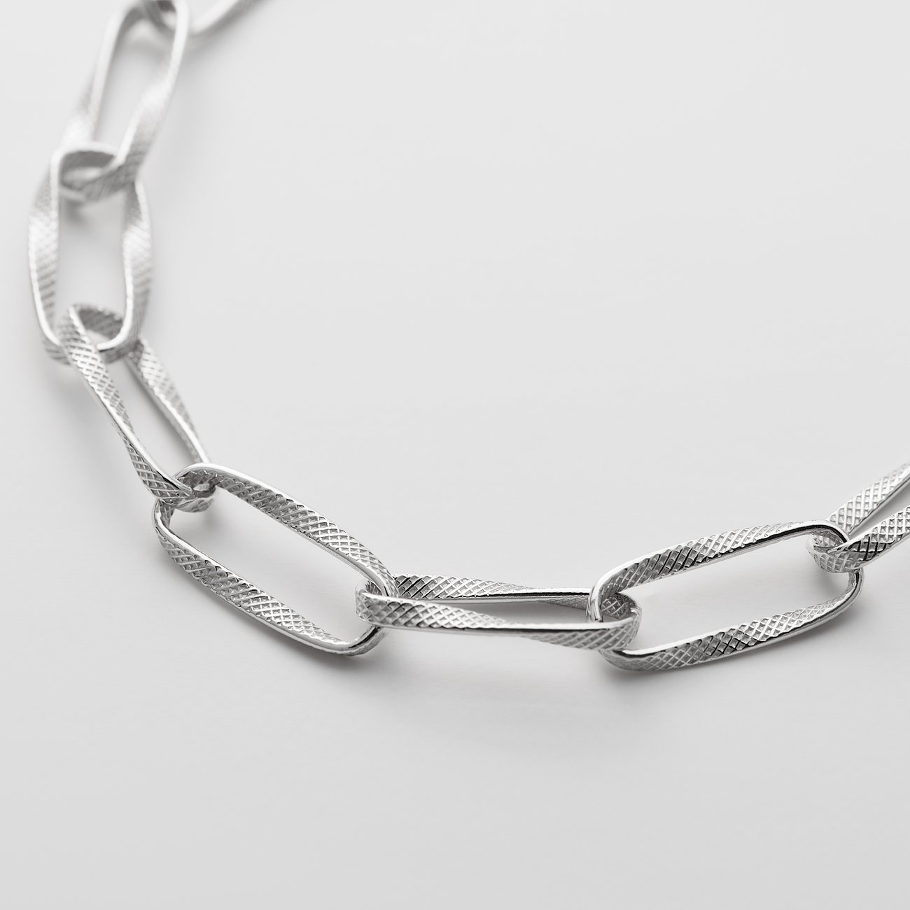 Närbild av ett CHRIST-armband i återvunnet 925 silver. De ovala länkarna har en präglad textur.