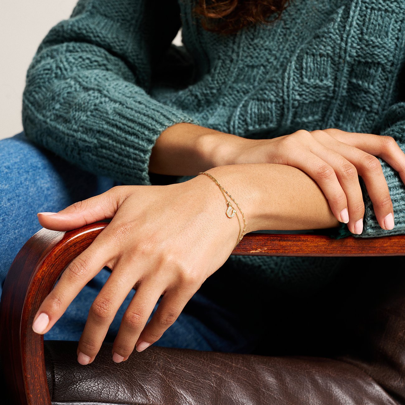 Am Handgelenk einer Person getragenes Fossil Armband aus goldfarbenem Edelstahl mit zwei Ketten und einem runden Glasstein.