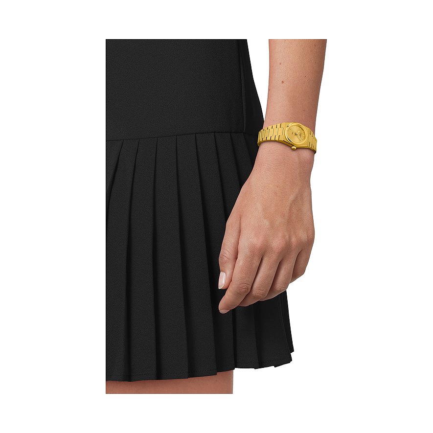 Eine Tissot Damenuhr aus gelbem Edelstahl am Handgelenk einer Person, die ein schwarzes Kleid trägt.