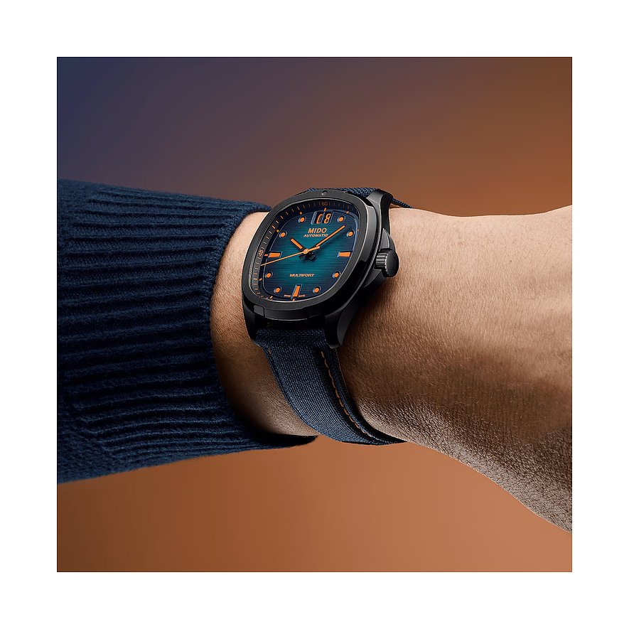 Am Handgelenk getragene Mido Herrenuhr aus blauem Textilband und Gehäuse aus schwarzem Edelstahl.
