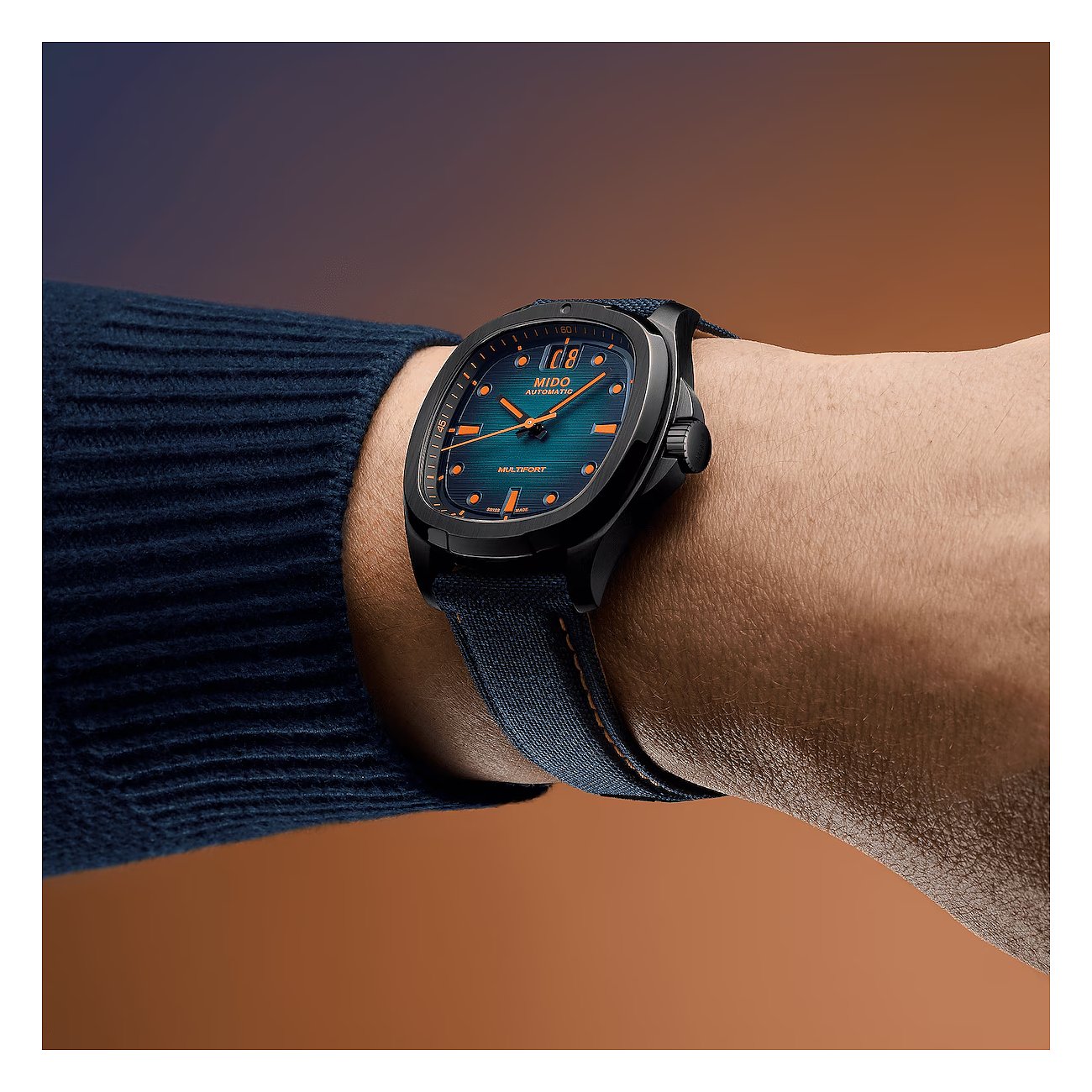 Am Handgelenk getragene Mido Herrenuhr aus blauem Textilband und Gehäuse aus schwarzem Edelstahl.