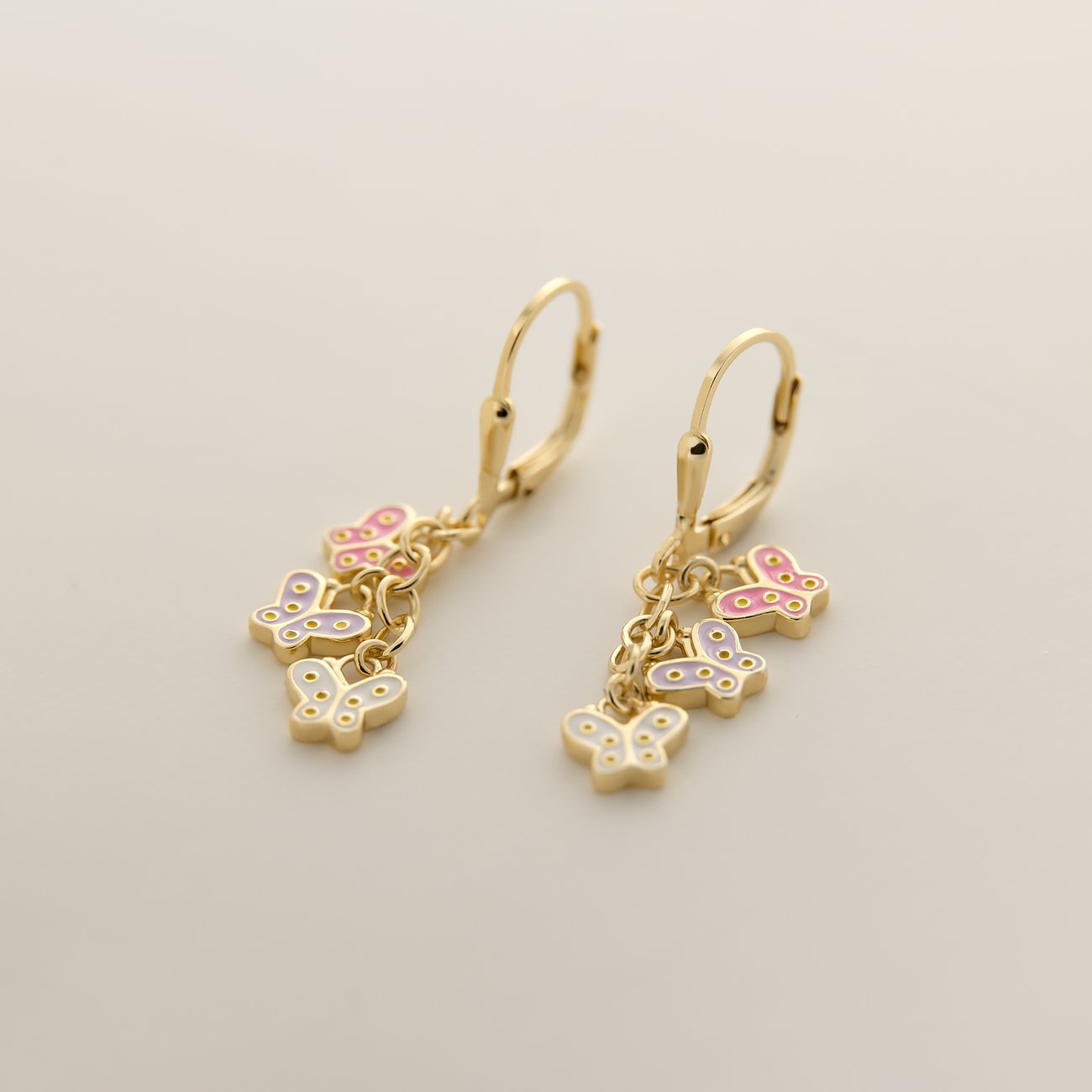 FAVS Ohrschmuck aus vergoldetem Silber mit bunten Emaille-Schmetterlingen an Ketten in Nahaufnahme.