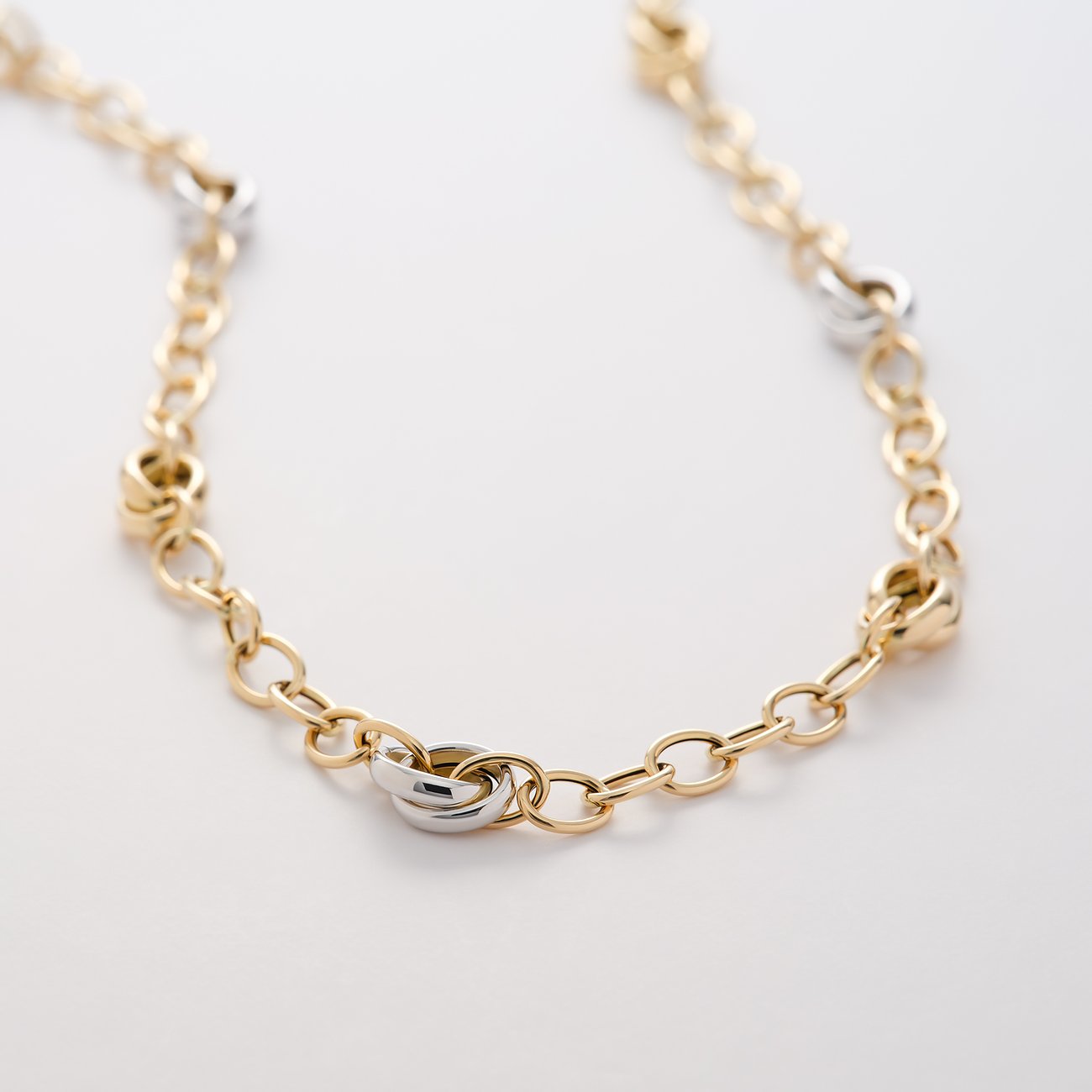 CHRIST Halskette aus Gelbgold und Weißgold mit ineinandergreifenden Ringen, detailreich auf weißem Hintergrund.