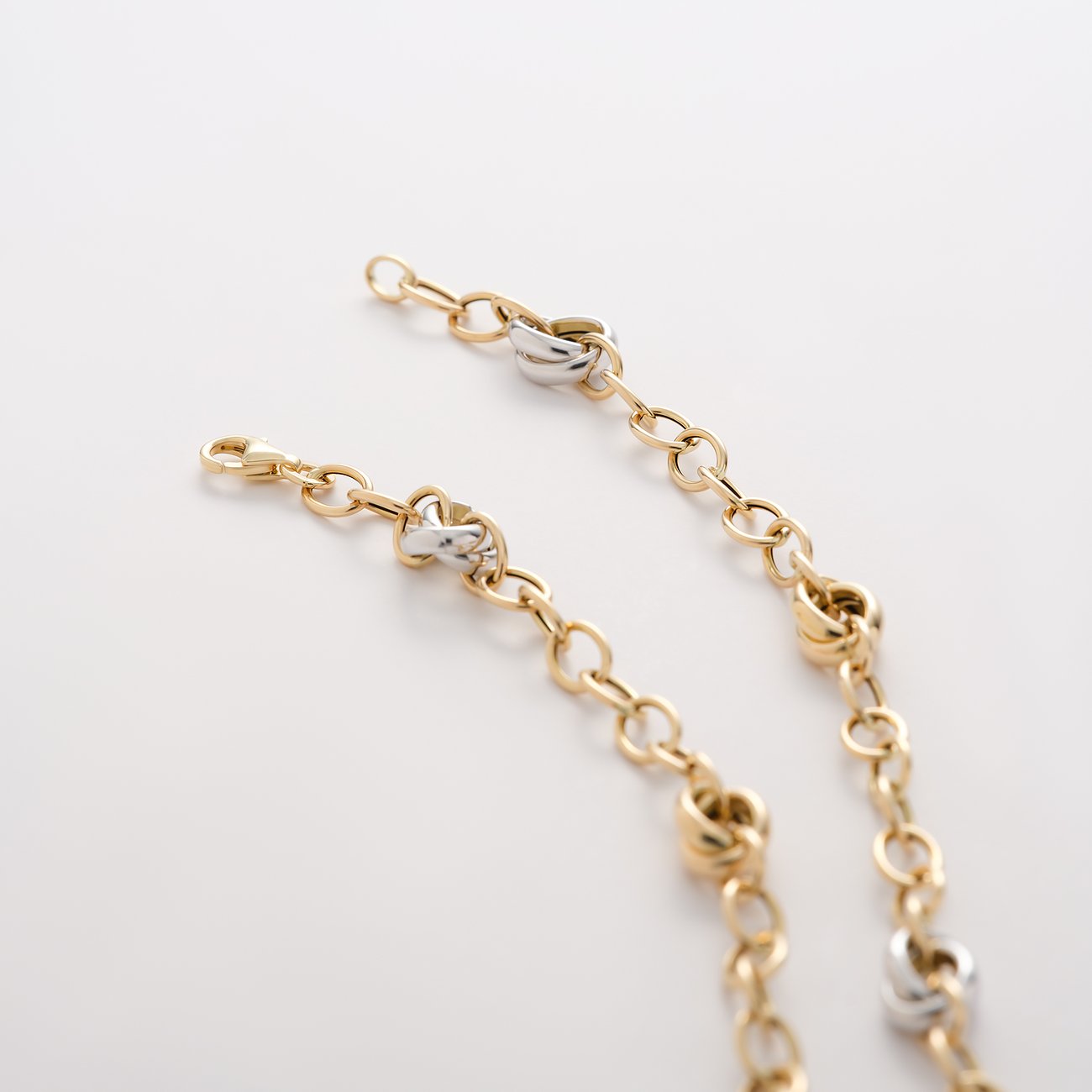 CHRIST Halsschmuck aus Gelb- und Weißgold mit Knotendetails, nah aufgenommen auf weißem Hintergrund.