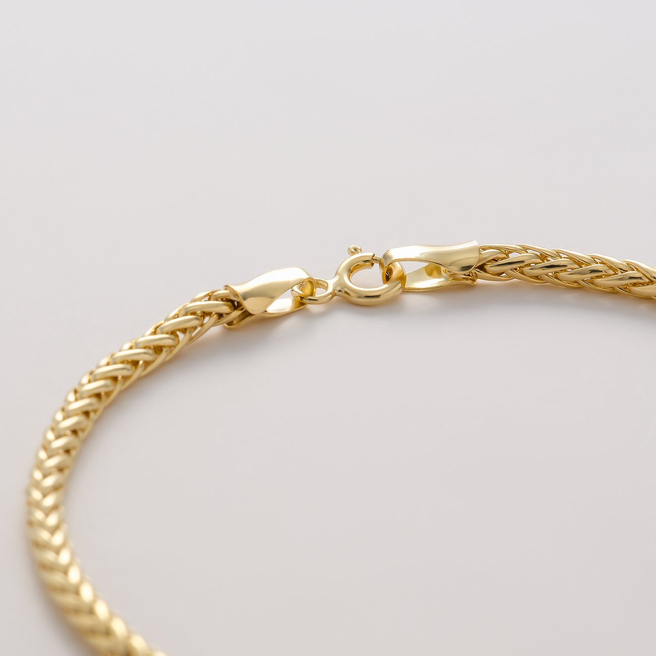 Nahaufnahme eines CHRIST 375er Gelbgold Armbands mit einer strukturierten Kette im Weizen-Design und Verschluss.